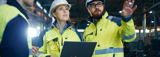 Male and Female Industrial Engineers Talk with Factory Worker while Using Laptop